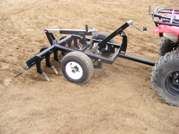 Red ATV with Arena Rake attached, smoothing arena footing