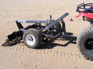 A red Arena Rake is parked in the sandy arena.