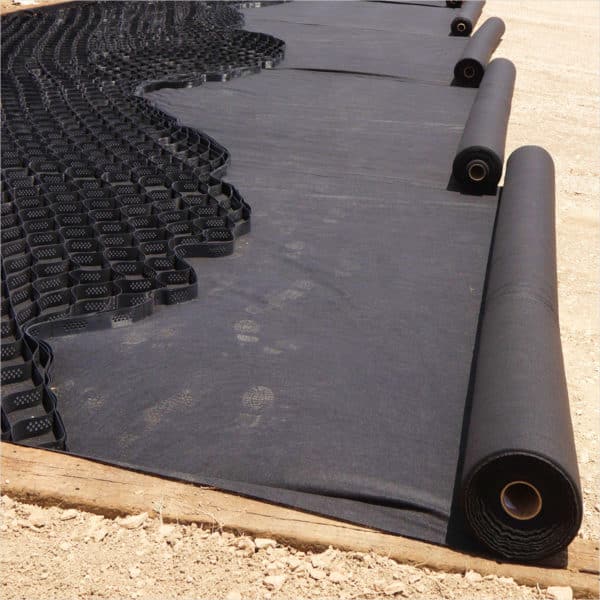 A roll of black Geotextile is laid out on the ground.