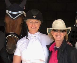 About three women posing for a photo with a horse.