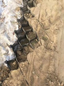 A black plastic grate is placed on a snowy road.