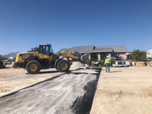 A construction crew is working on a road in front of a house, transforming it into an arena-like gallery space.