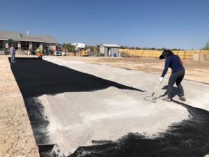 A woman is pouring black sand in an arena.