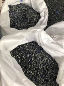 A bag of black and blue gravel is displayed on a table in an arena.