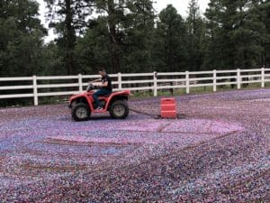 A man riding an atv through a field of colorful confetti in an arena.