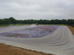 A tractor is working on a field, transforming it into an arena-like gravel gallery.