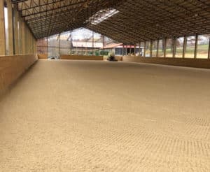 A large indoor arena with a sand floor.