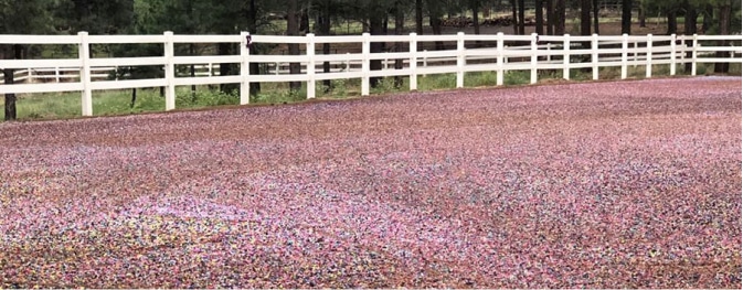 A pink gravel road with a white fence in the background, featuring a mix of rubber mulch and foam footing.