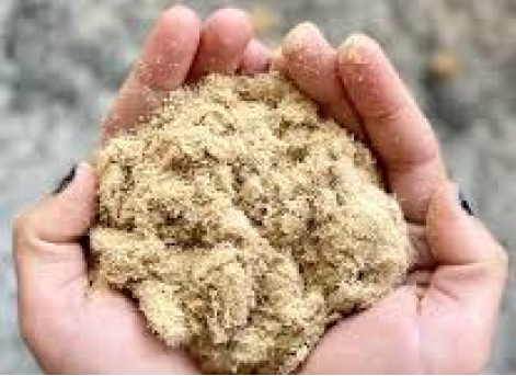 A person holding a handful of dust-free sand in their hands.