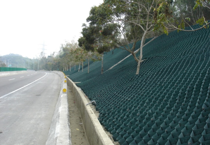 A green chain link fence on the side of a road.