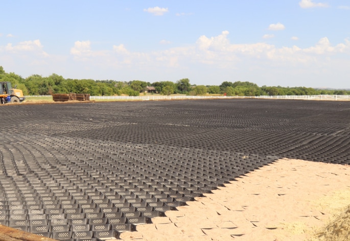 A construction site with a large area of black netting.
