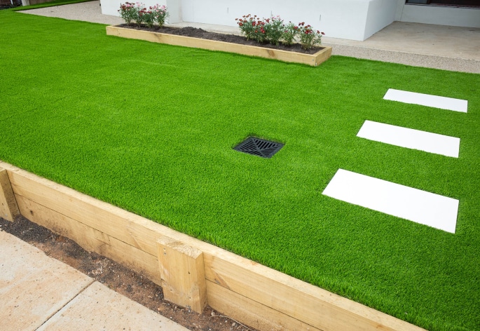 A backyard with artificial grass and a wooden fence.