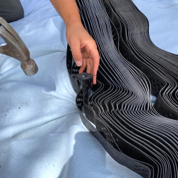 A person is working on a piece of black metal.