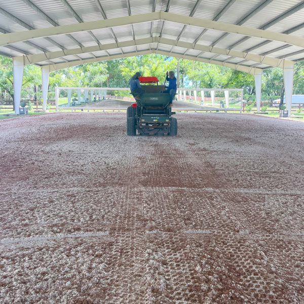 A horse is riding on a dirt track with Noviun Fiber and Elastomer Horse Footing in a barn.