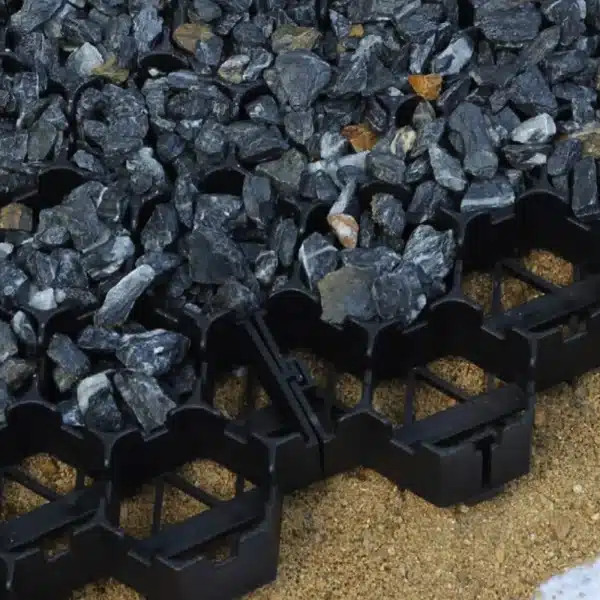 A black gravel grate sitting on the sand.